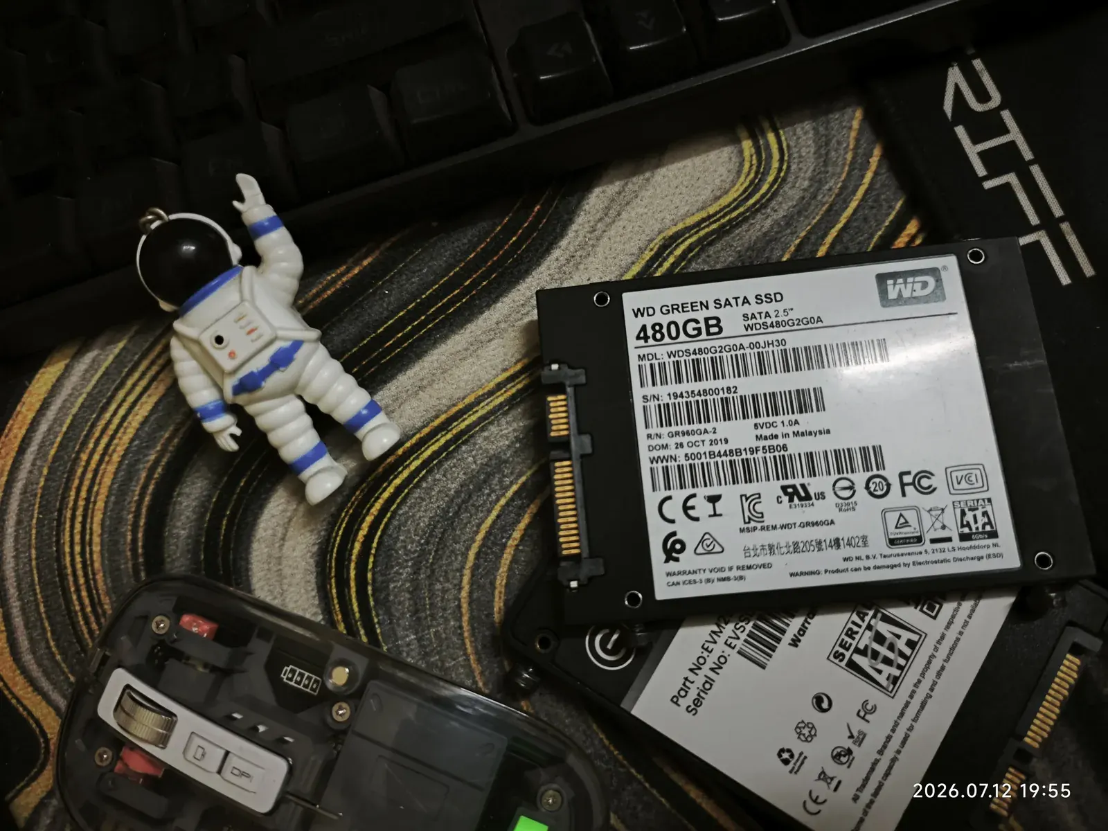 An SSD, a mouse and an astronaut keychain on a desk mat